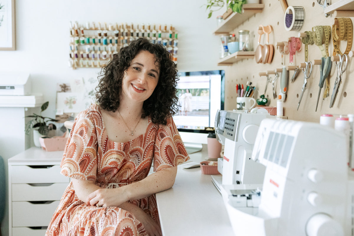 Megan Nielsen smiling at her sewing desk in her workroom